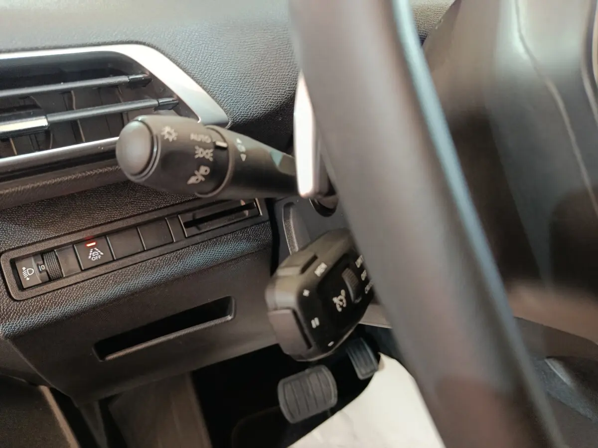 Gros plan sur la partie gauche du tableau de bord et volant cuir du Peugeot 5008 gris clair 2023.