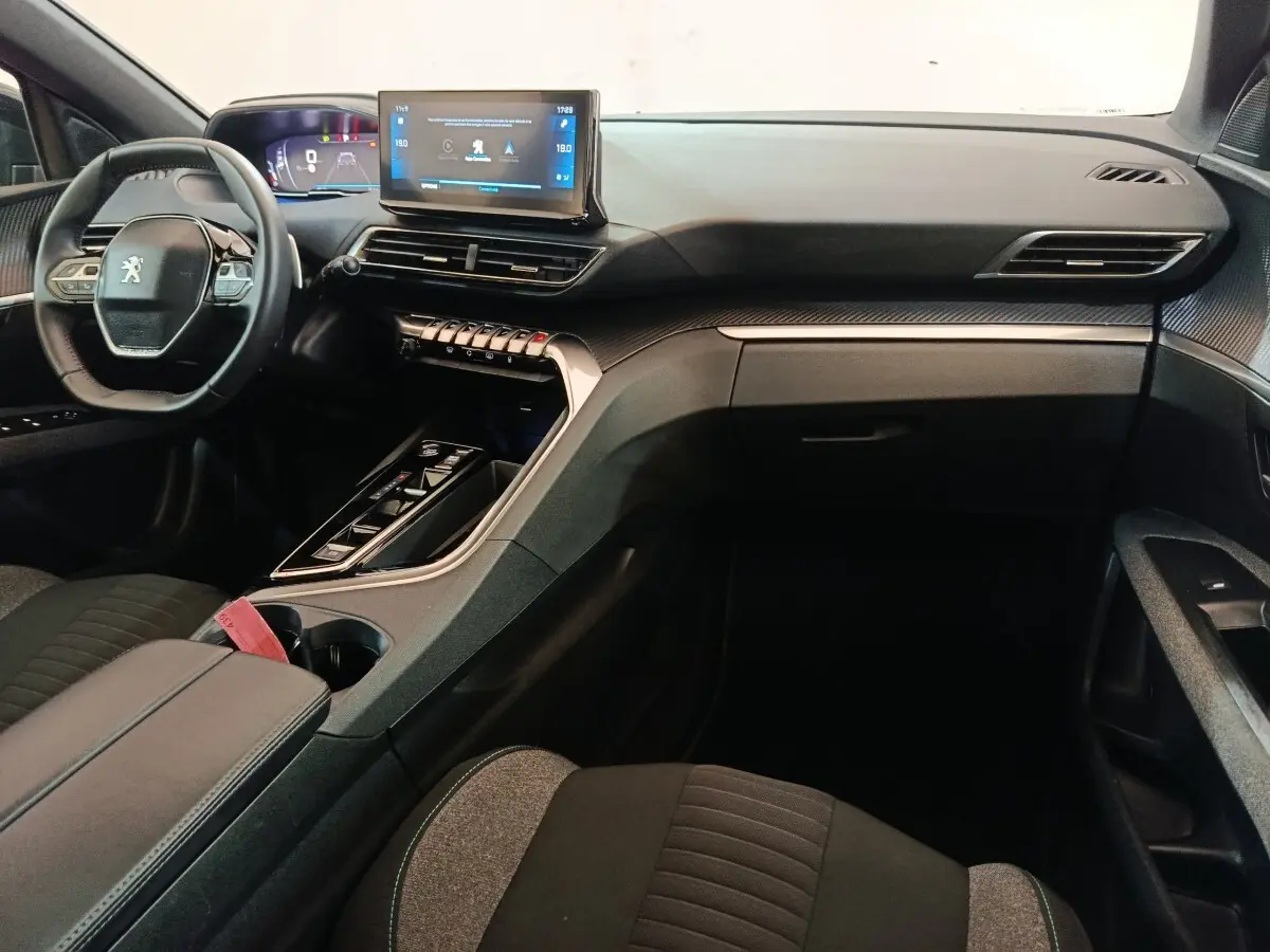 Intérieur avant droit du Peugeot 5008 gris clair 2023, volant cuir multifonctions et écran tactile central visible.