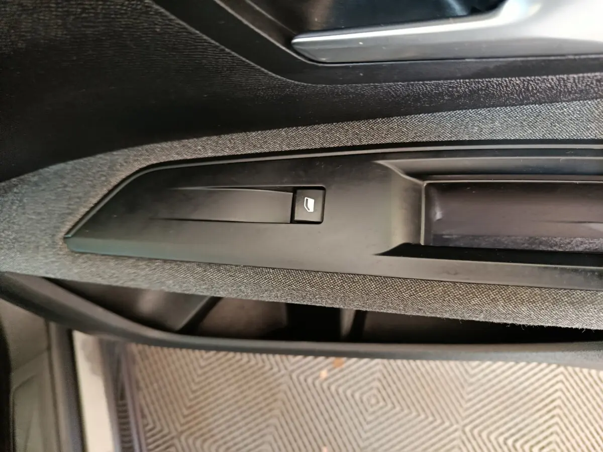 Détail du bouton de commande de vitre électrique sur la porte intérieure côté conducteur du Peugeot 5008 gris clair 2023.