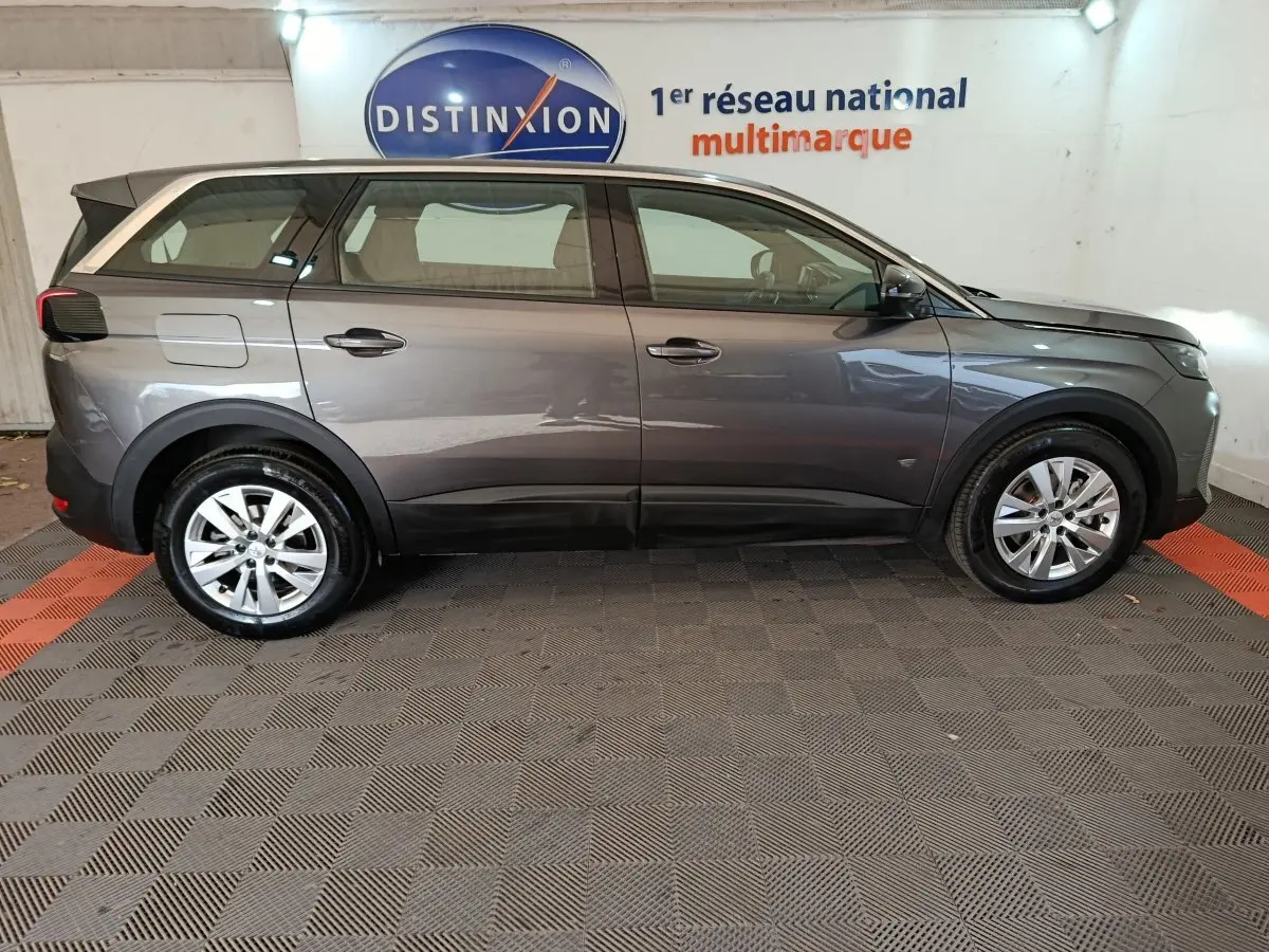 Profil droit d'un Peugeot 5008 gris clair 2023, SUV familial avec jantes alliage et lignes épurées.