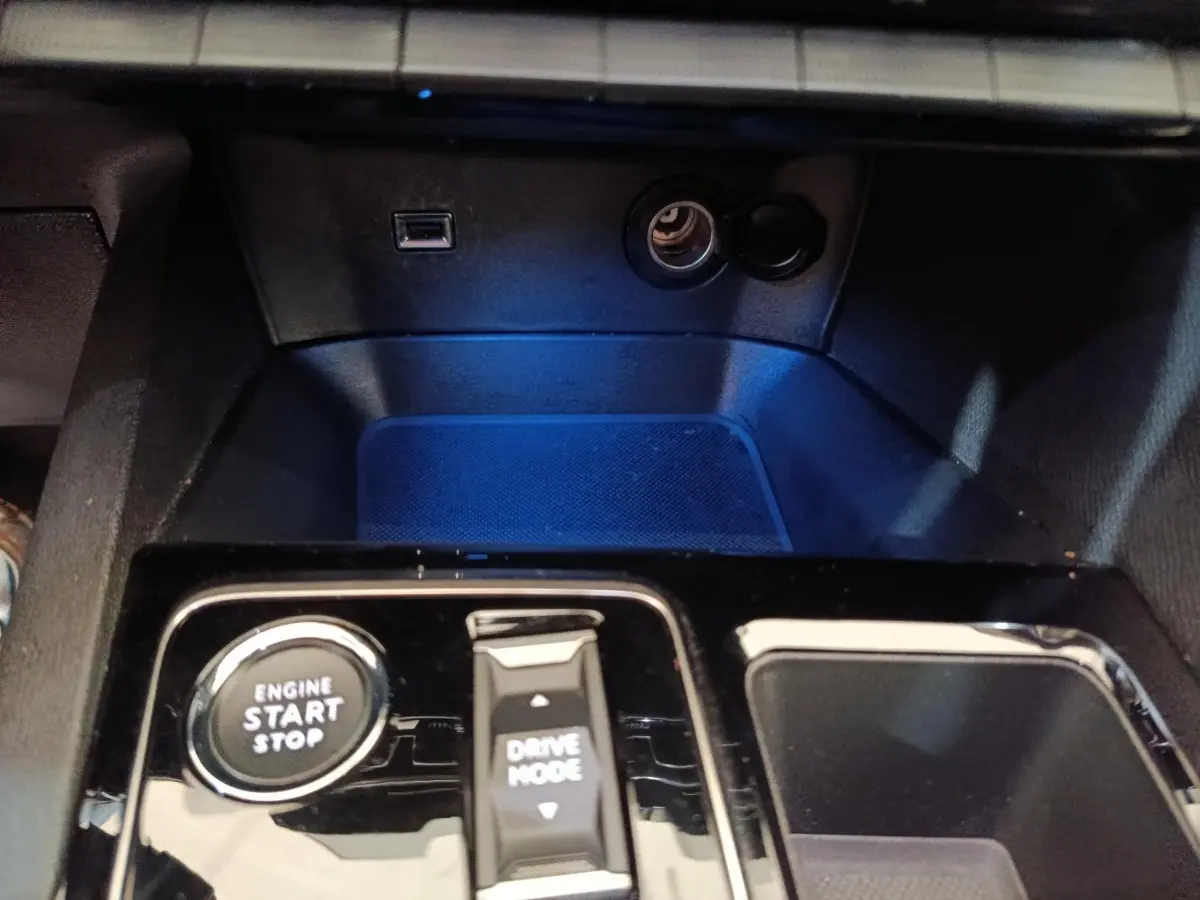 Gros plan sur la console centrale noire brillante du Peugeot 5008 gris clair, avec bouton démarrage et commande Drive Mode.