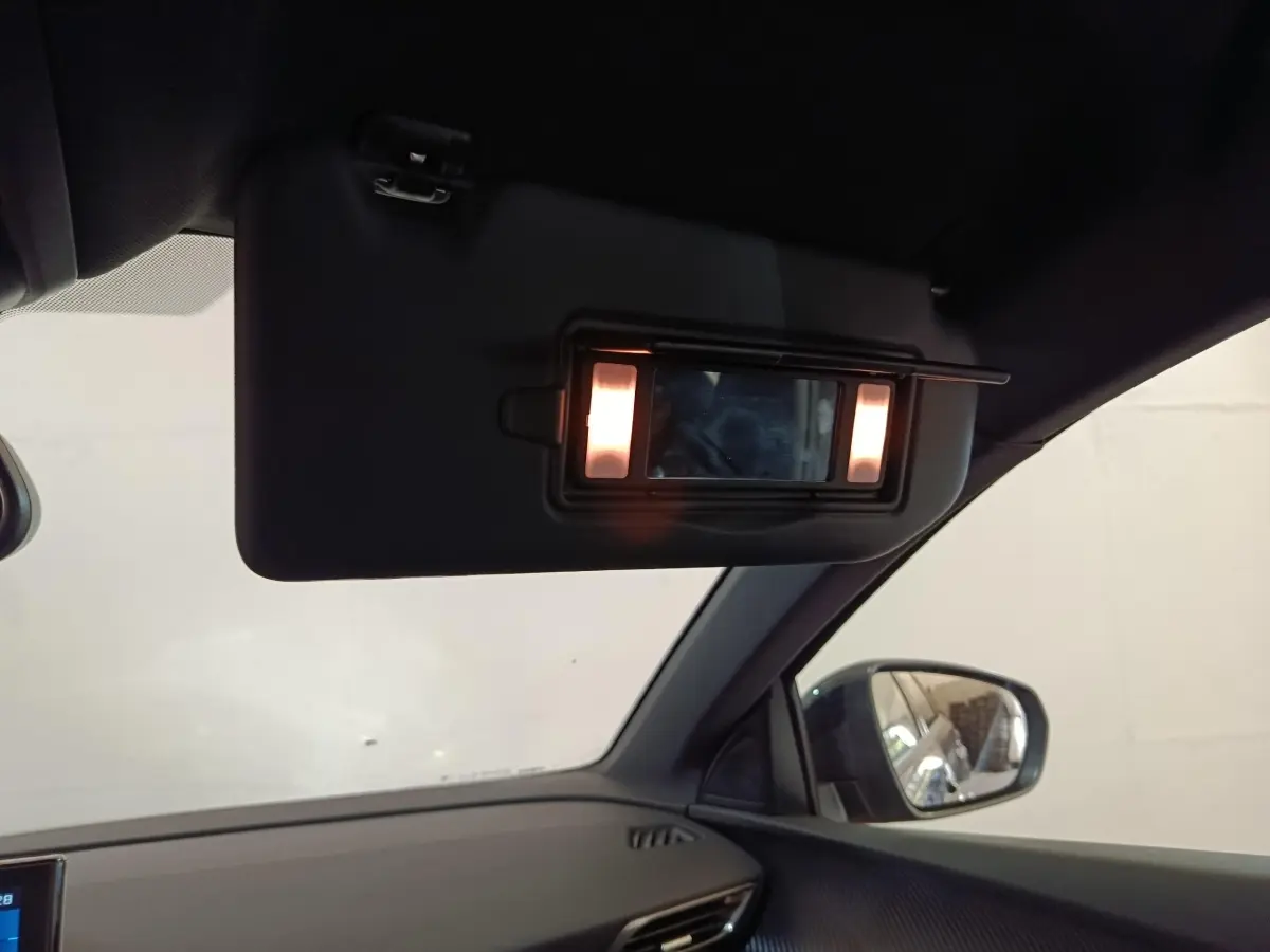 Détail intérieur du pare-soleil avec miroir éclairé côté droit dans un Peugeot 5008 gris clair 2023.