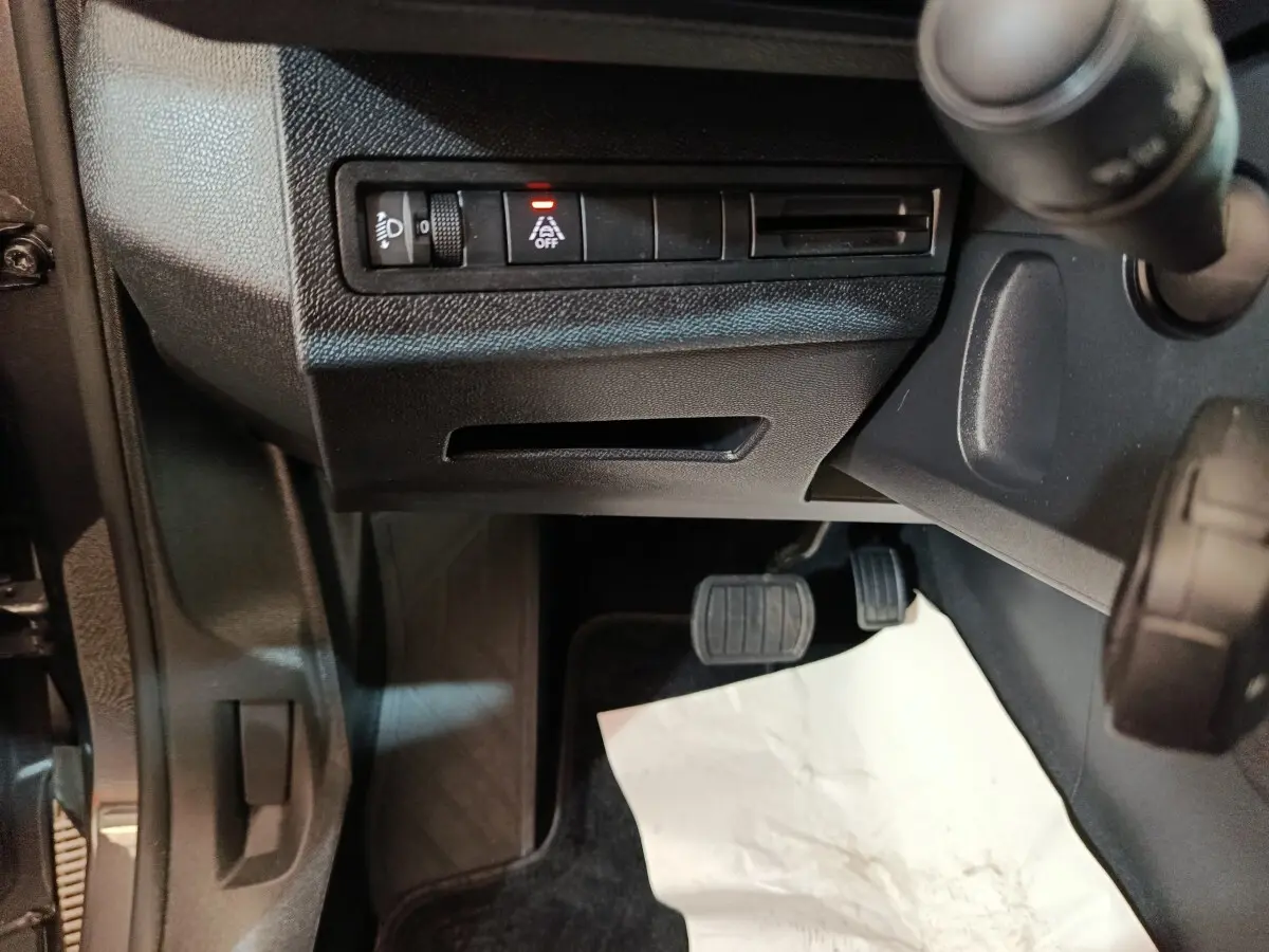 Vue intérieure côté conducteur du Peugeot 5008 2023, montrant les pédales et commandes sous le tableau de bord noir.
