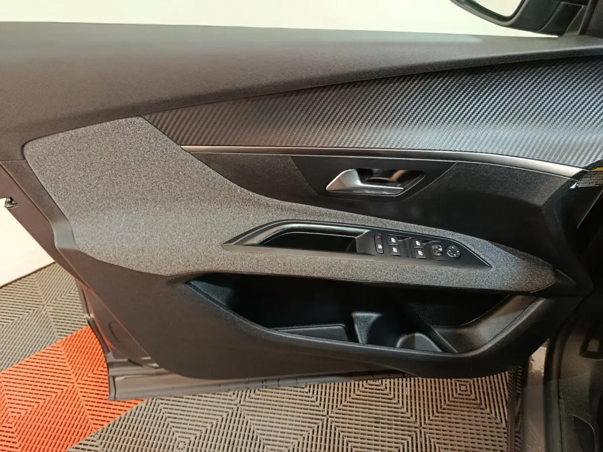 Vue rapprochée de la porte avant gauche de la Peugeot 5008 gris clair, avec commandes des vitres et poignée intégrée.