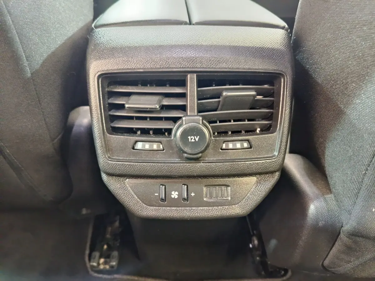 Vue rapprochée des aérateurs arrière et prise 12V noirs du Peugeot 5008 gris clair, avec commandes de ventilation.
