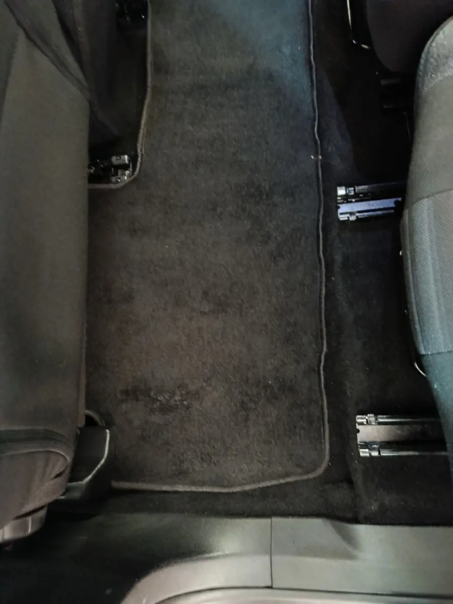 Vue rapprochée du sol entre les sièges arrière d’un Peugeot 5008 gris clair, avec tapis de sol noir.