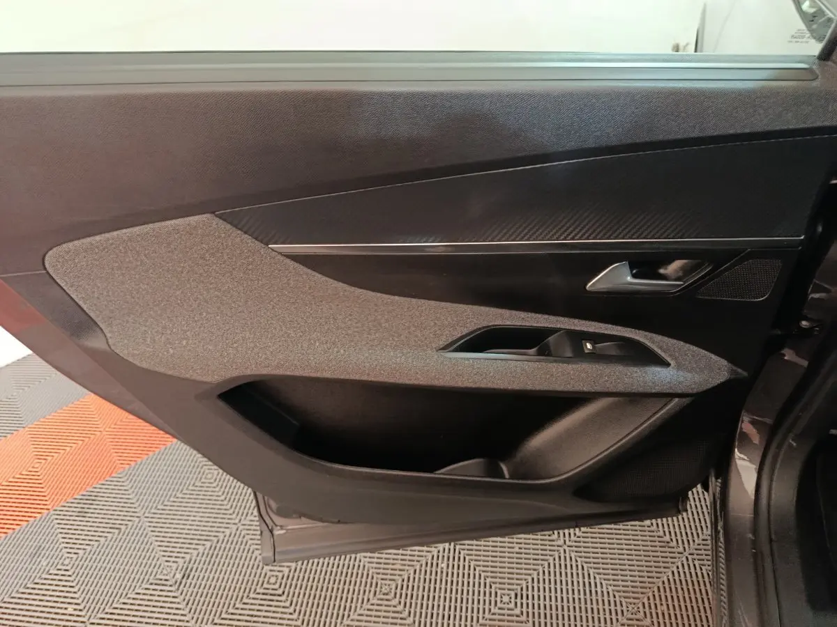 Vue rapprochée de la porte intérieure côté gauche du Peugeot 5008 gris clair, avec garniture textile et insert noir brillant.