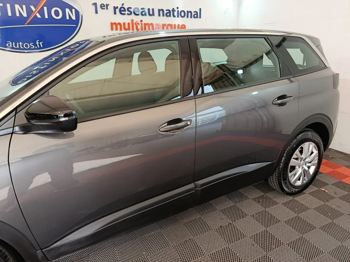 Profil droit du Peugeot 5008 gris clair 2023, mettant en valeur ses lignes épurées et ses rétroviseurs noirs brillants.