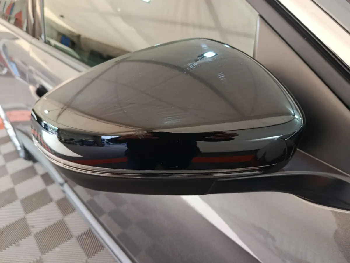 Rétroviseur noir brillant côté gauche d’un Peugeot 5008 gris clair, vue rapprochée sur la portière.