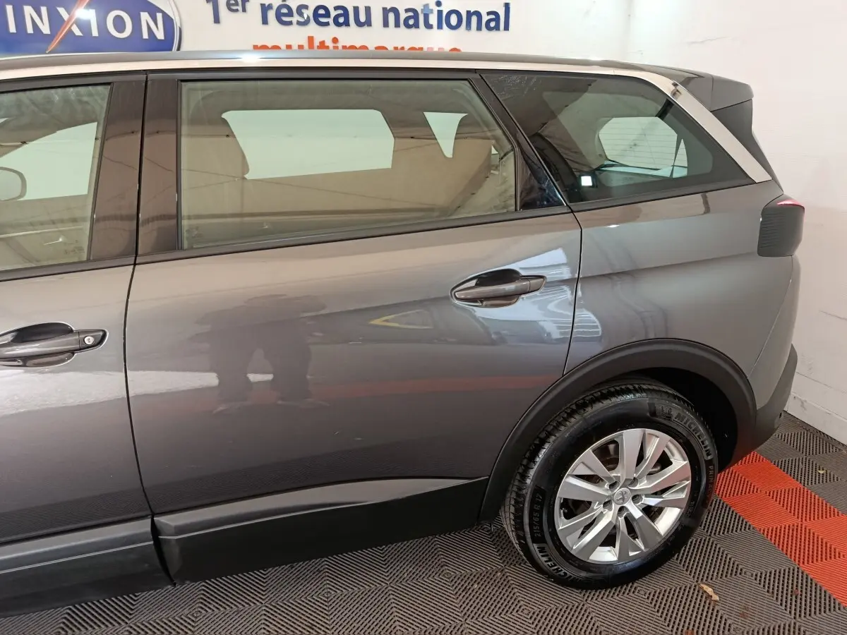 Vue latérale côté droit du Peugeot 5008 gris clair, mettant en valeur la porte arrière et la roue arrière.