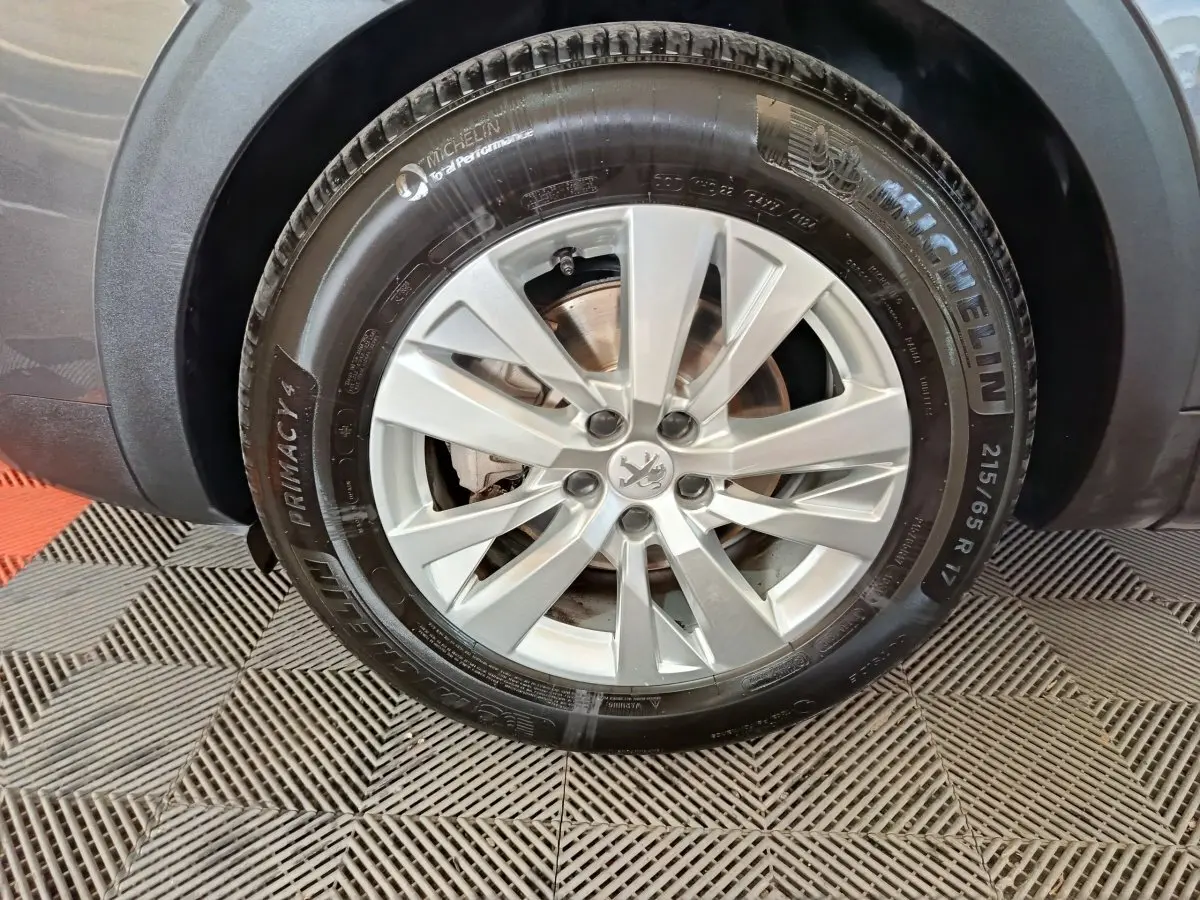 Gros plan sur la roue avant droite du Peugeot 5008 gris clair, avec jante alliage et pneu Michelin.