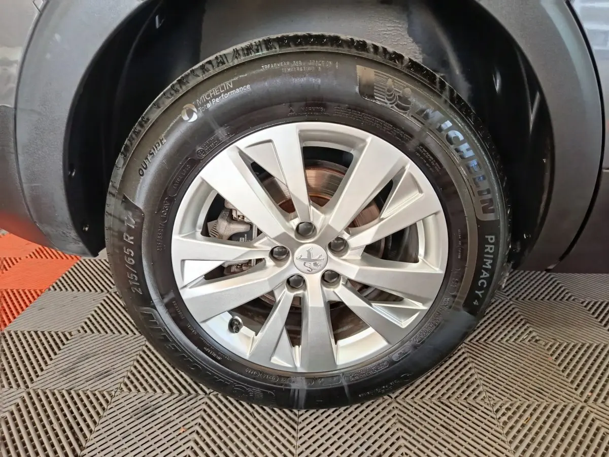 Gros plan sur la roue avant droite du Peugeot 5008 gris clair, avec jante alliage et pneu Michelin Primacy 4.