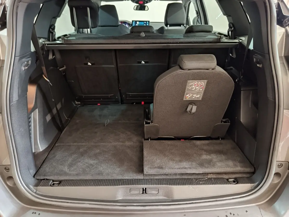 Coffre ouvert vu de l'arrière d'un Peugeot 5008 gris clair, avec siège arrière droit relevé et plancher plat.