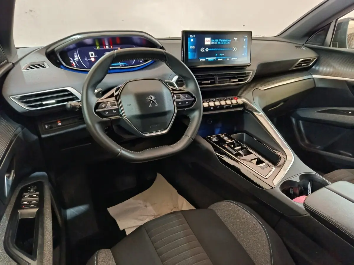 Vue intérieure côté conducteur du Peugeot 5008 2023, volant cuir multifonctions et écran tactile central lumineux.
