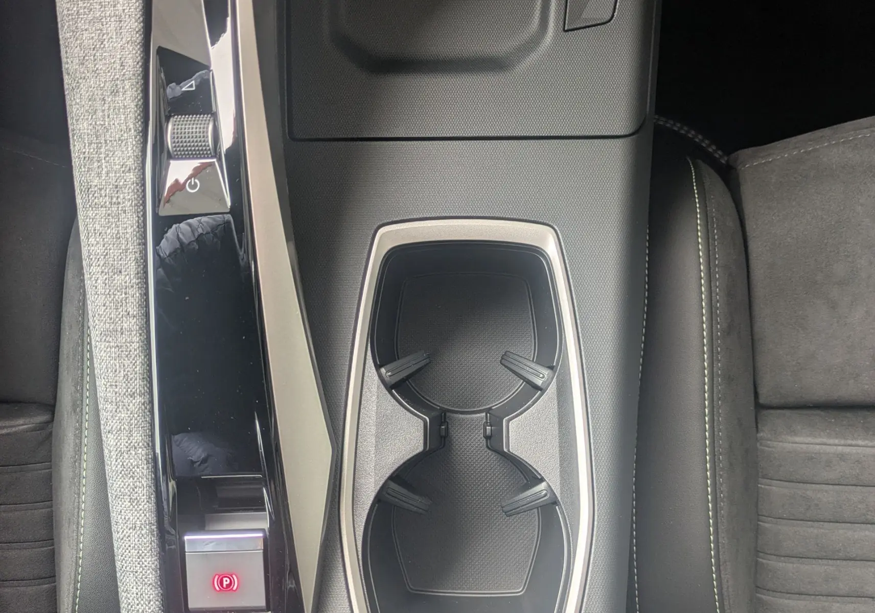 Vue plongeante sur la console centrale du Peugeot 3008 Hybrid 2026, avec porte-gobelets et sellerie Alcantara noire.