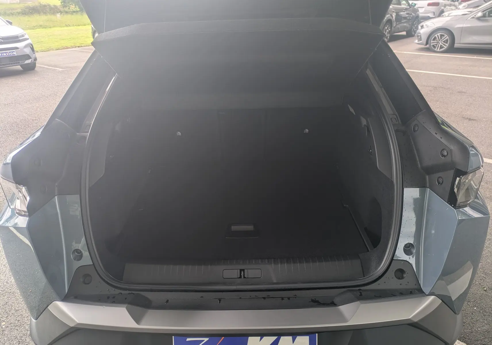Coffre ouvert vu de l'arrière d'un Peugeot 3008 Hybrid 145 bleu Ingaro avec détails noirs perla, en extérieur.