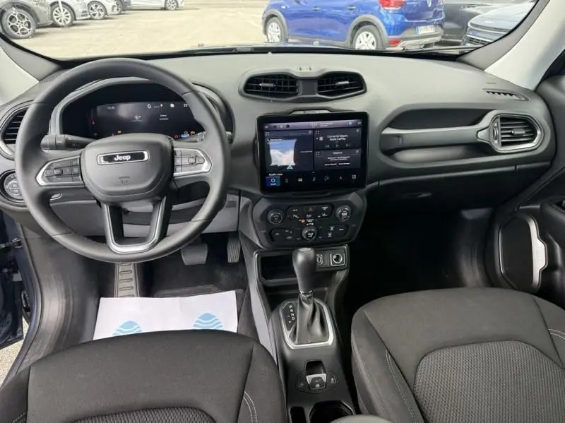 Vue intérieure frontale du tableau de bord et volant du Jeep Renegade 2024, avec écran tactile central et sellerie noire.