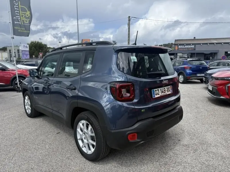 Jeep Renegade bleu métal vue 3/4 arrière droit, avec feux arrière carrés et toit noir, stationné en extérieur.