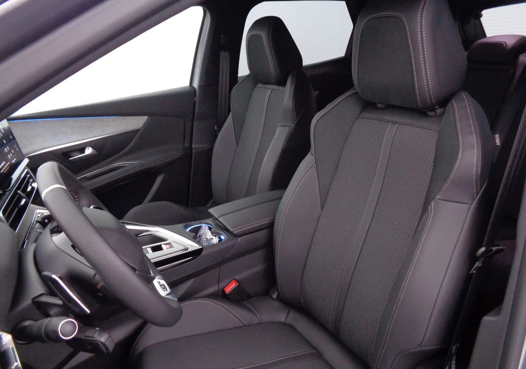 Intérieur du Peugeot 3008 2023, vue côté conducteur, sièges en cuir noir avec surpiqûres contrastées et volant sport.