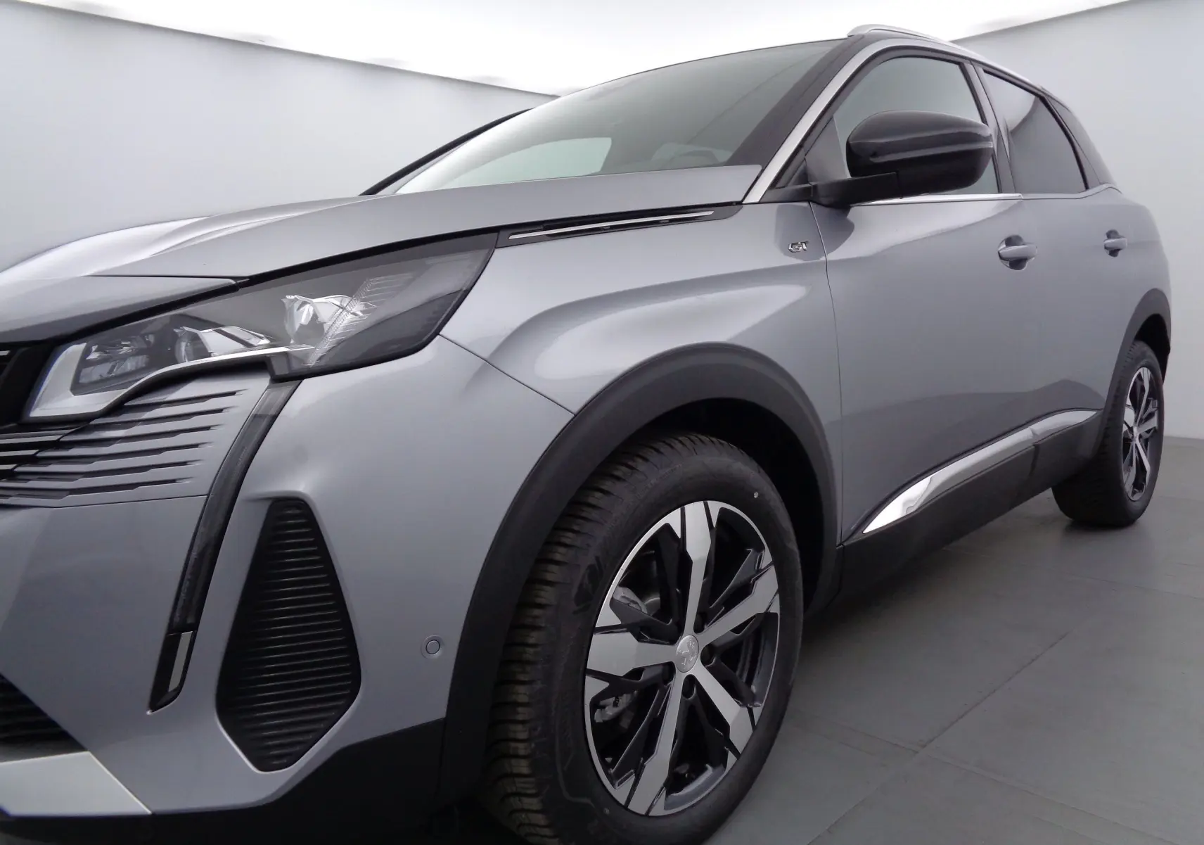 Vue 3/4 avant droit d'un Peugeot 3008 gris Artense métallisé avec jantes alliage et badge GT visible sur l'aile.