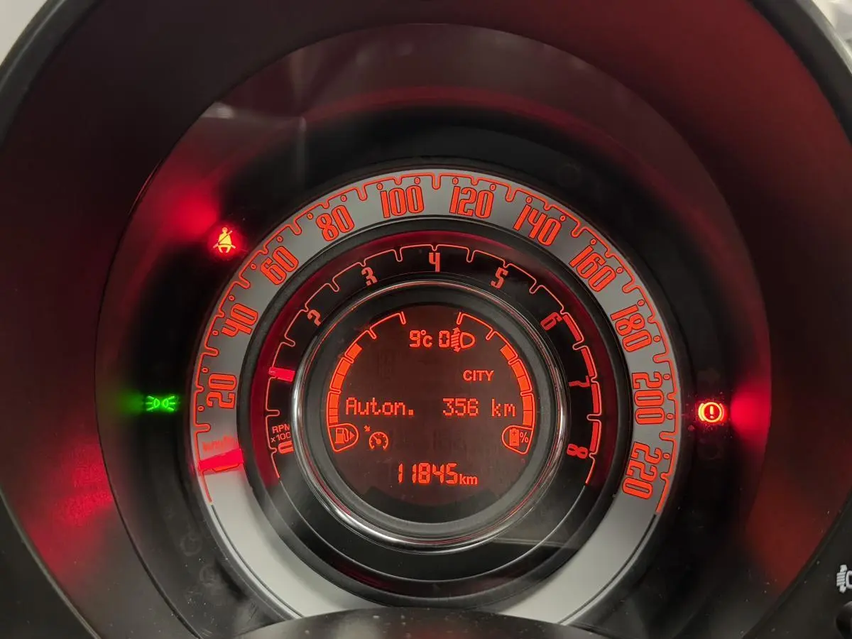 Gros plan sur le combiné d'instrumentation rouge de la Fiat 500 Cabriolet noire affichant 11845 km et autonomie 356 km.