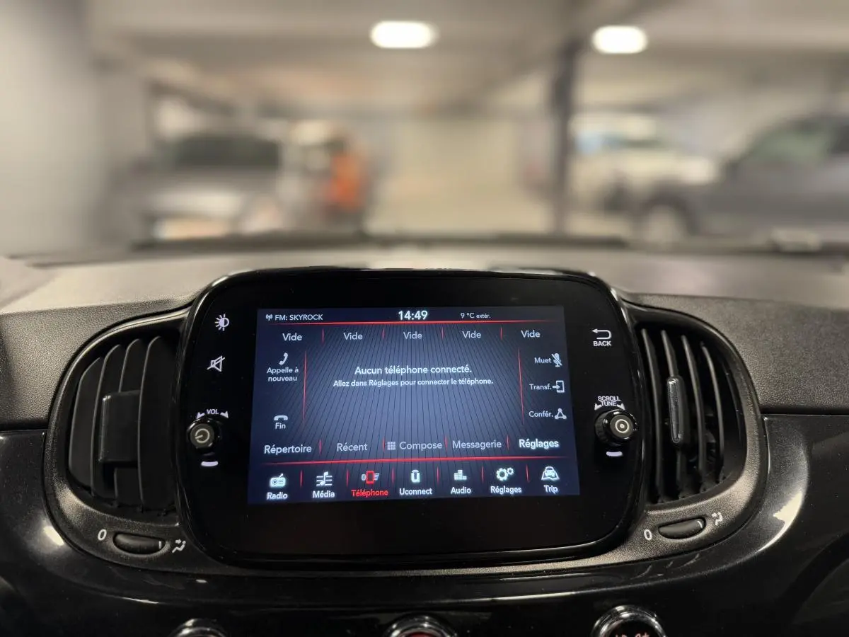 Écran tactile central allumé du tableau de bord noir de la Fiat 500 Cabriolet 2024 avec commandes multimédia visibles.