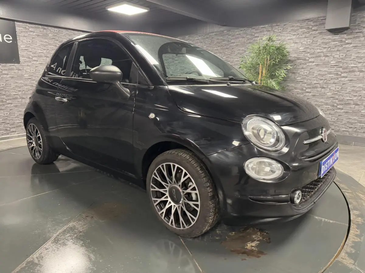 Fiat 500 noire vue 3/4 avant droit, avec jantes alliage et calandre distinctive dans un showroom.
