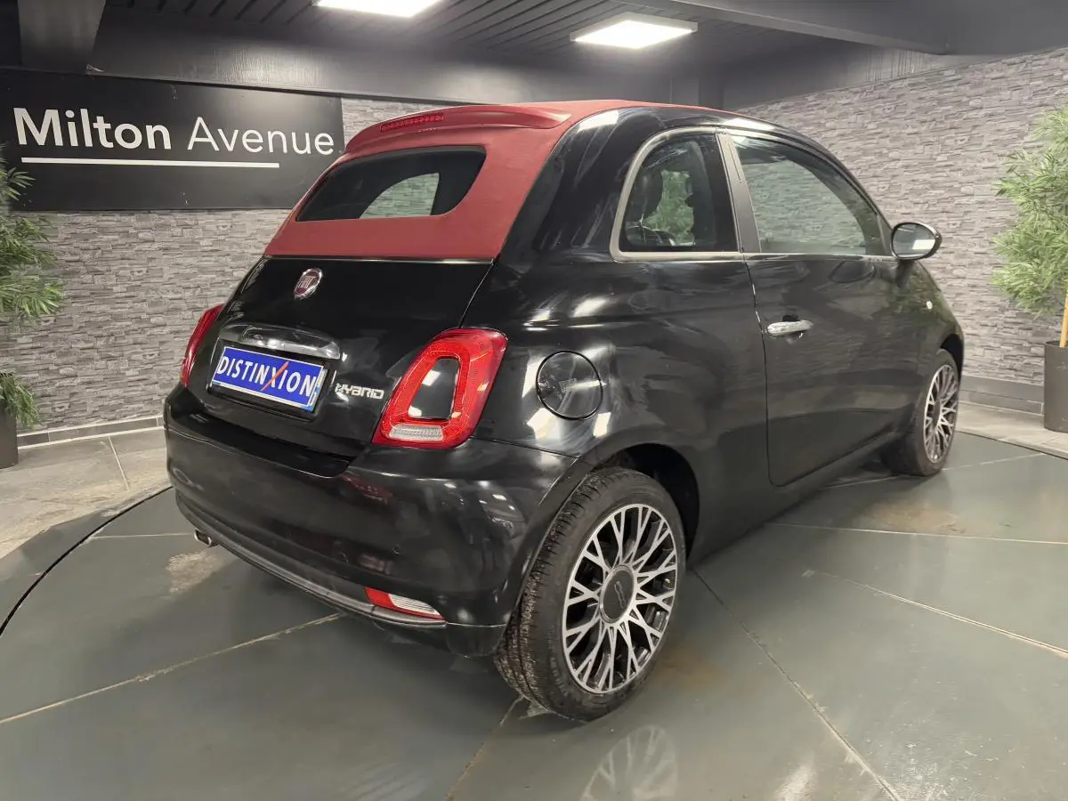 Vue 3/4 arrière droite d'une Fiat 500 noire avec capote rouge et jantes alliage 16 pouces Spider.