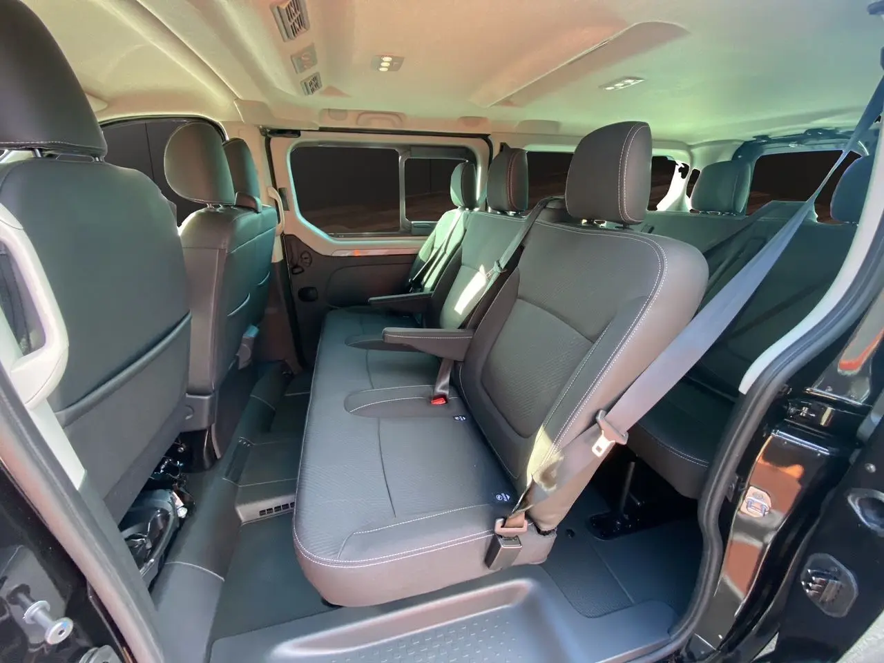 Vue intérieure côté gauche du Renault Trafic Combi noir 2025 montrant les sièges tissu noir et la porte coulissante ouverte.