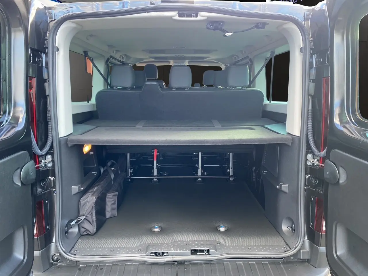 Vue arrière du Renault Trafic Combi noir 2025, coffre ouvert montrant banquette arrière et espace de chargement organisé.
