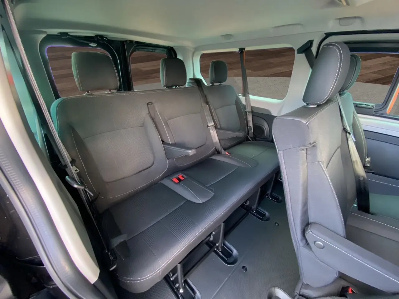Vue intérieure du Renault Trafic Combi noir montrant les sièges arrière en tissu noir avec ceintures et appuie-têtes.