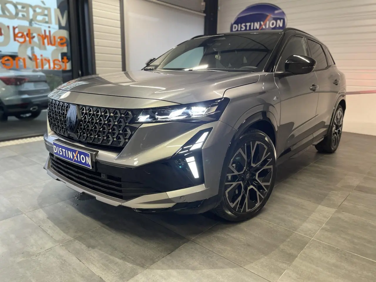 Renault Austral 2025 gris schiste métallisé avec toit noir étoilé, vue 3/4 avant droit mettant en valeur la calandre et les phares LED.