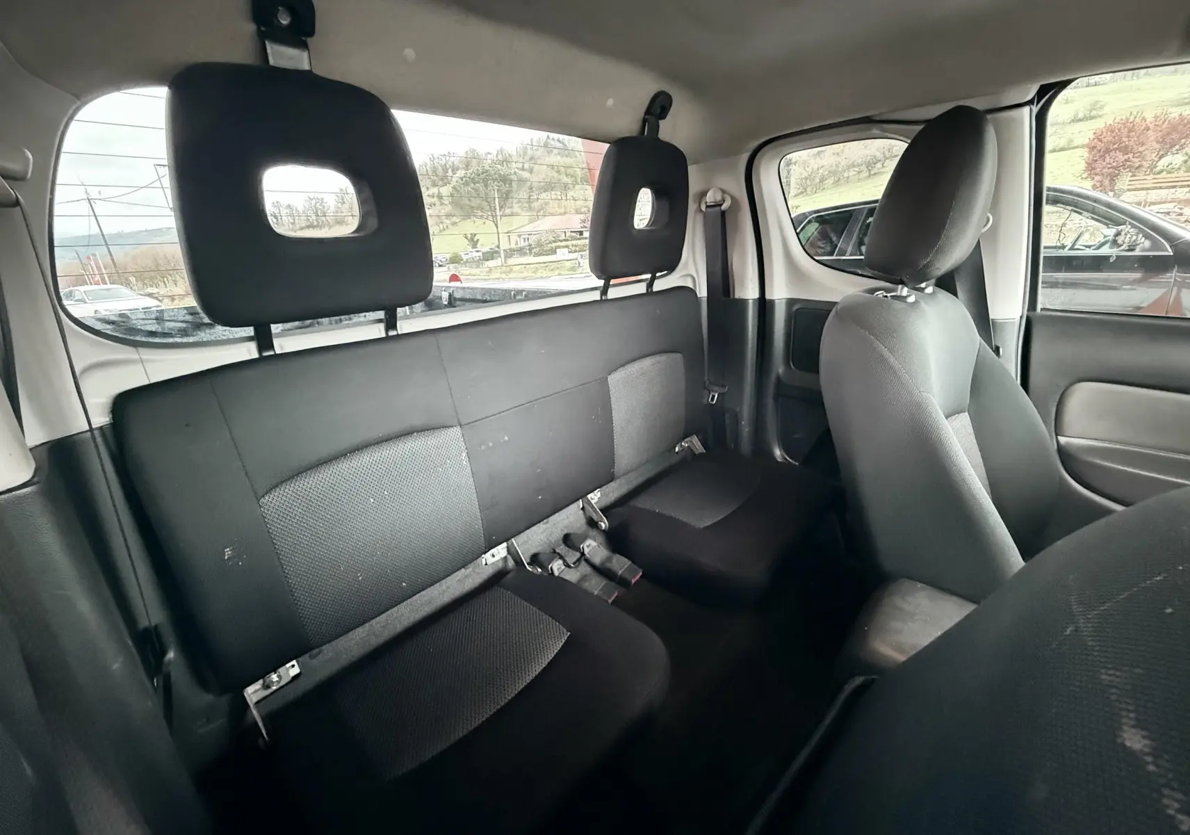 Vue intérieure arrière du Mitsubishi L200 Club Cab 2017, sièges noirs en tissu avec appuie-têtes ajourés.