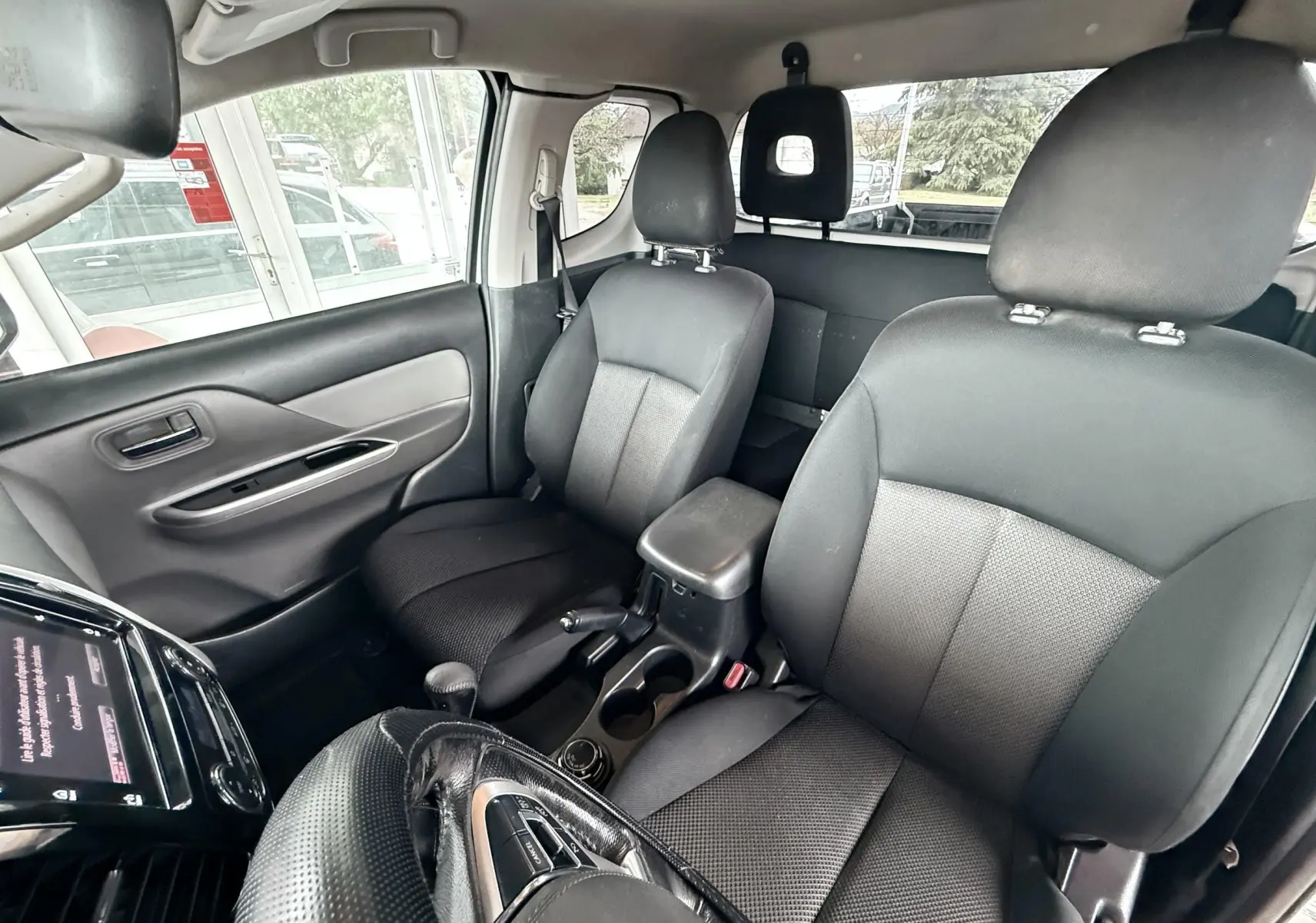 Vue intérieure du Mitsubishi L200 Club Cab 2017 montrant les sièges avant noirs et la console centrale entre eux.