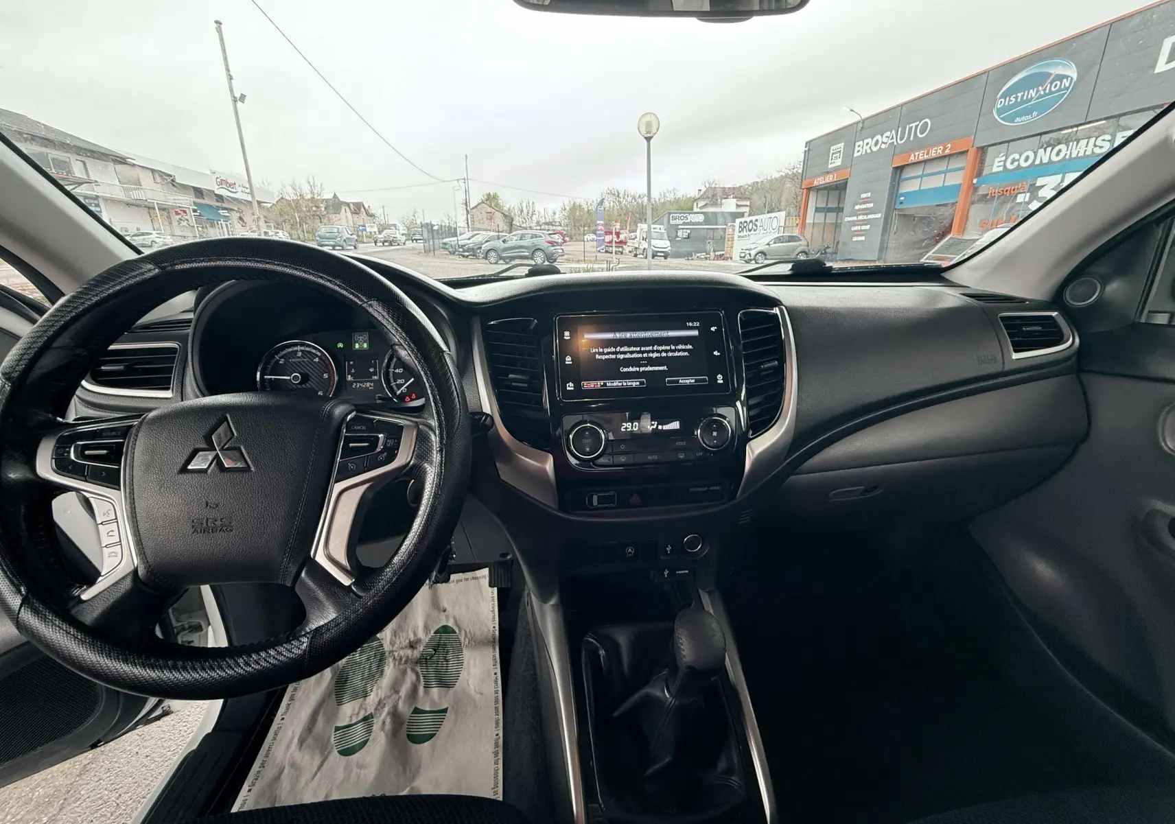 Vue intérieure avant du Mitsubishi L200 Club Cab 2017, tableau de bord noir avec volant multifonction et écran central tactile.