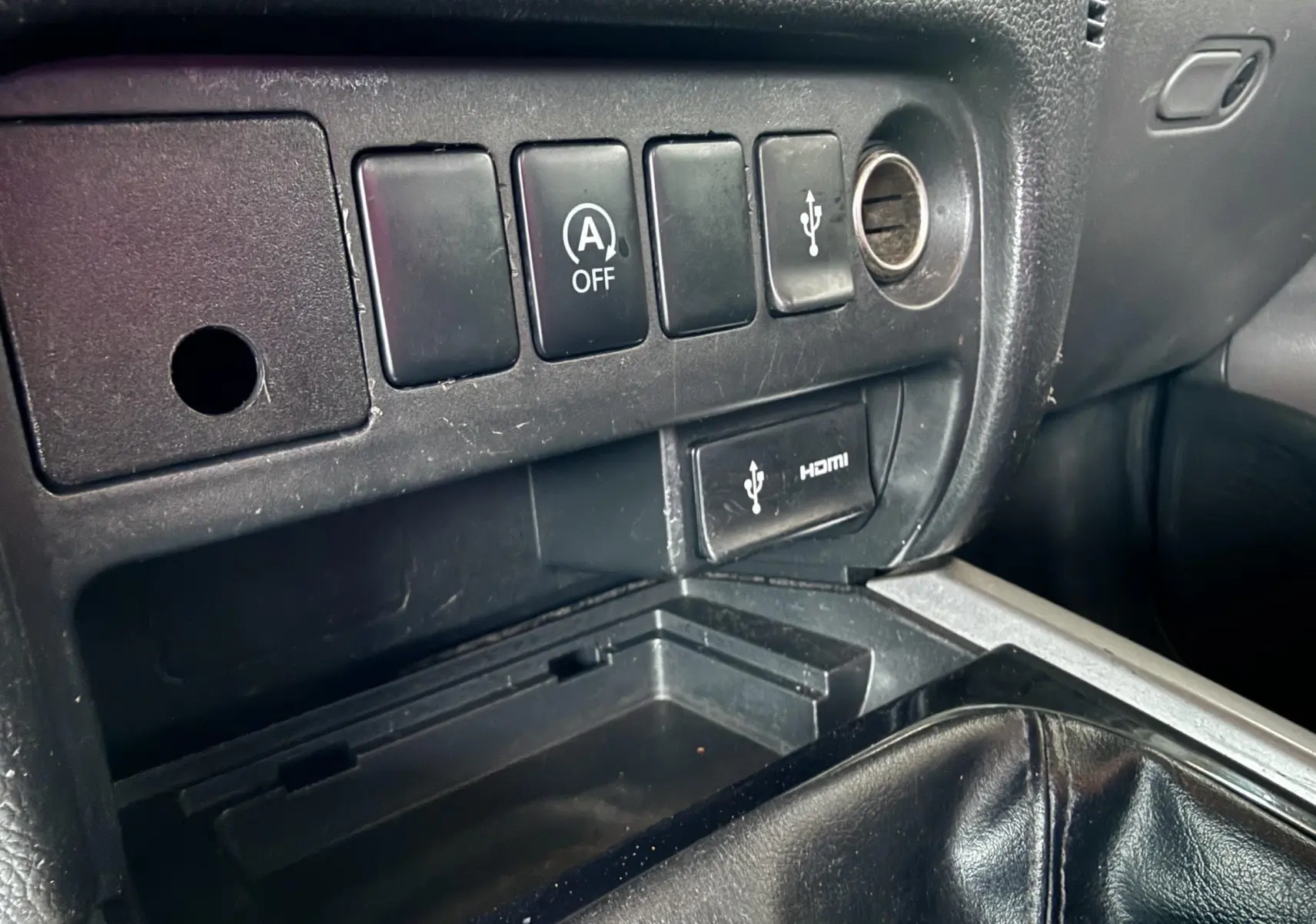 Gros plan sur la console centrale noire du Mitsubishi L200 Club Cab 2017, montrant les boutons de commande et prise USB/HDMI.