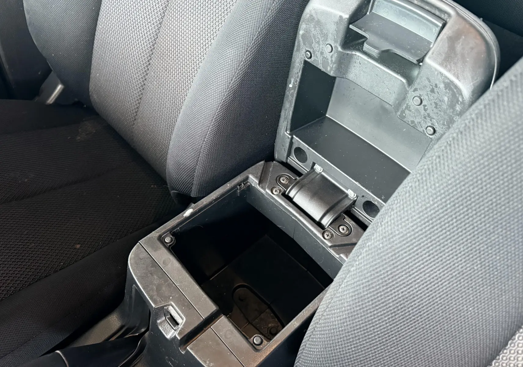 Vue rapprochée de la console centrale ouverte entre les sièges noirs du Mitsubishi L200 Club Cab 2017.