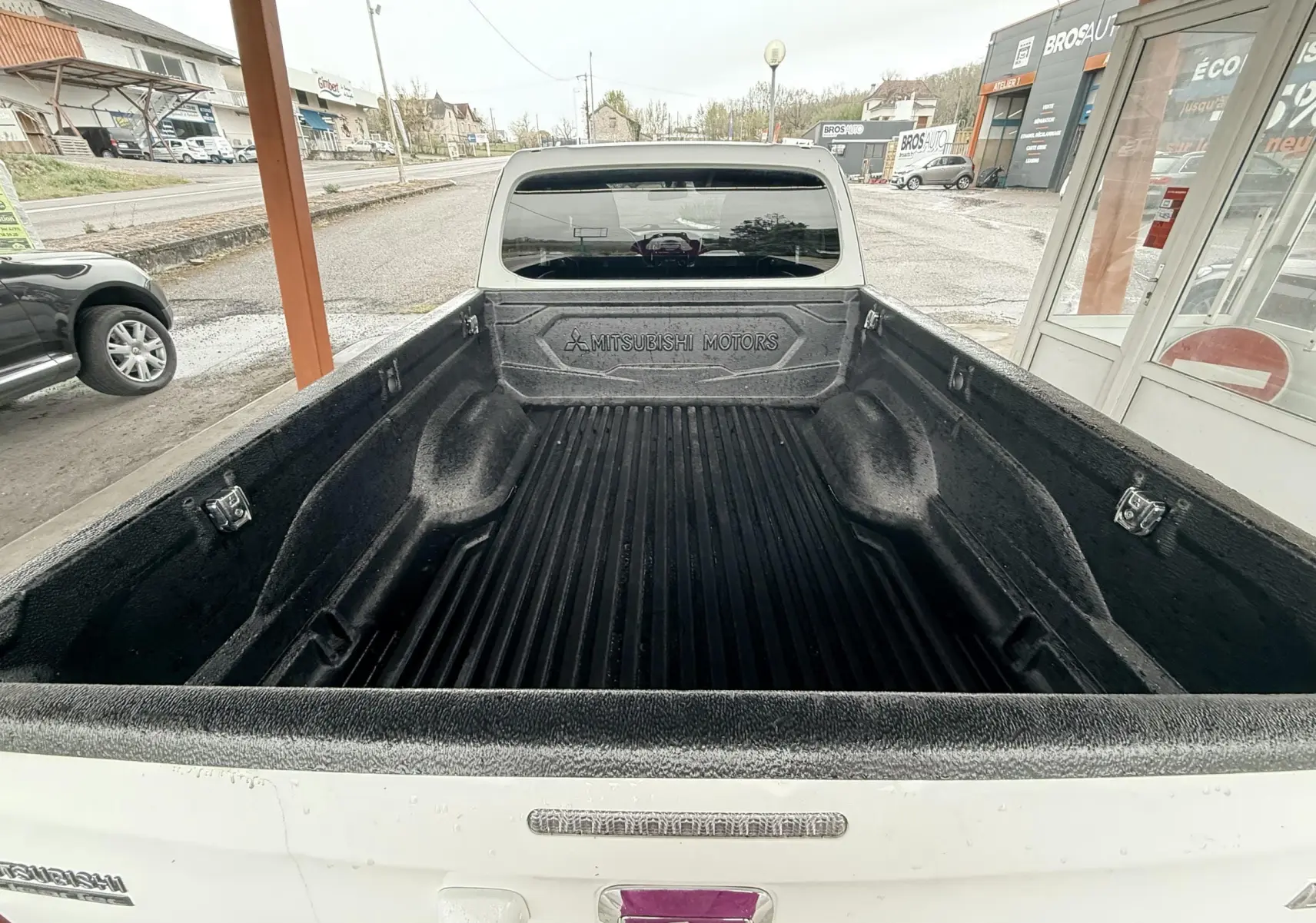 Vue arrière de la benne noire d’un Mitsubishi L200 Club Cab blanc, soulignant l’espace de chargement et le logo Mitsubishi Motors.