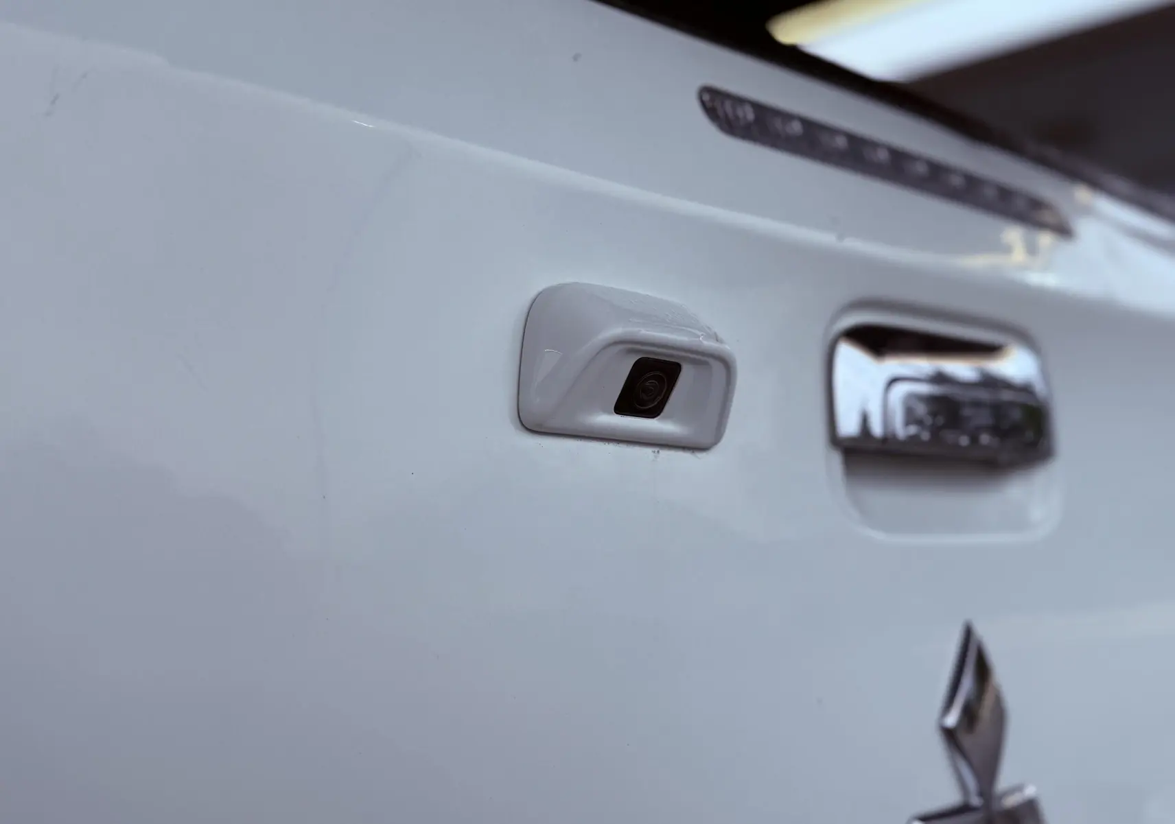 Gros plan sur la caméra de recul intégrée à la porte arrière blanche du Mitsubishi L200 Club Cab 2017.