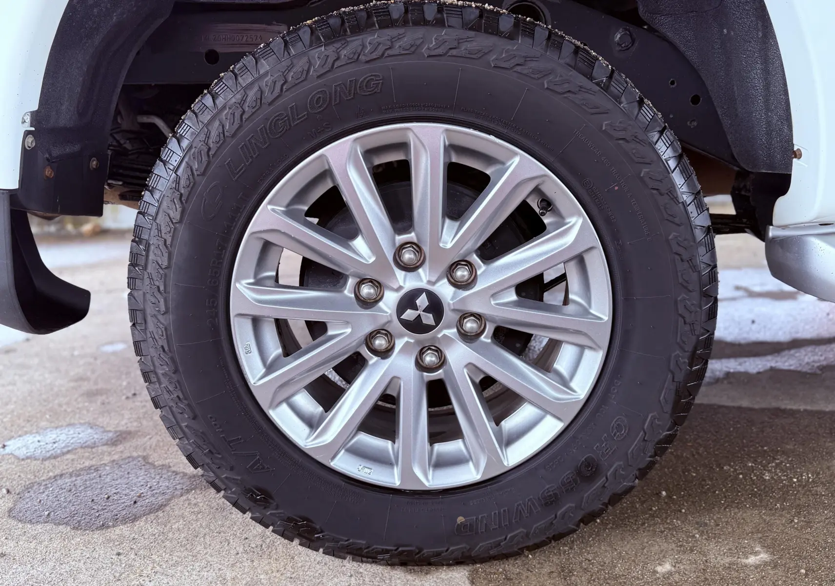 Gros plan sur la roue avant droite du Mitsubishi L200 blanc, mettant en valeur la jante alliage et le pneu tout-terrain.