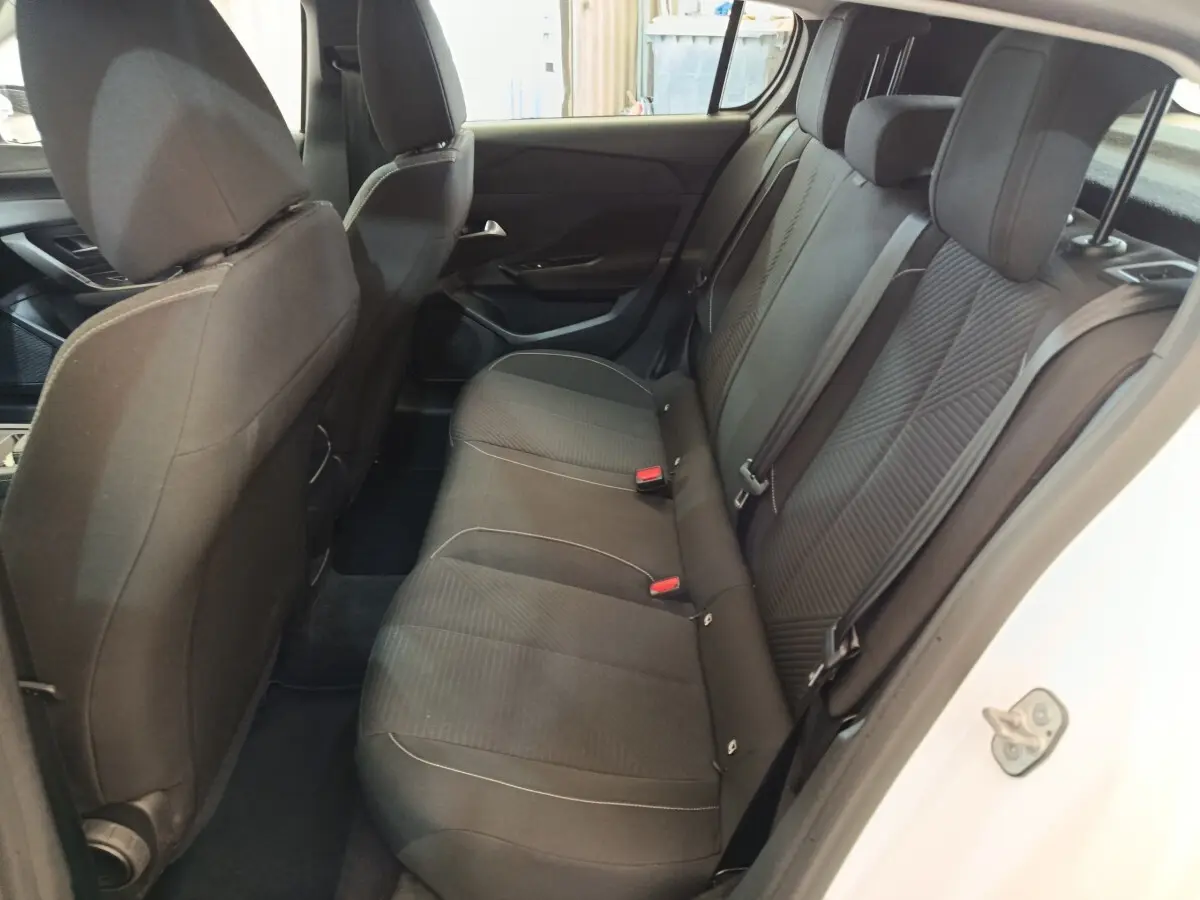 Vue intérieure côté droit des sièges arrière noirs d'une Peugeot 308 blanche, avec ceintures et appuie-têtes visibles.