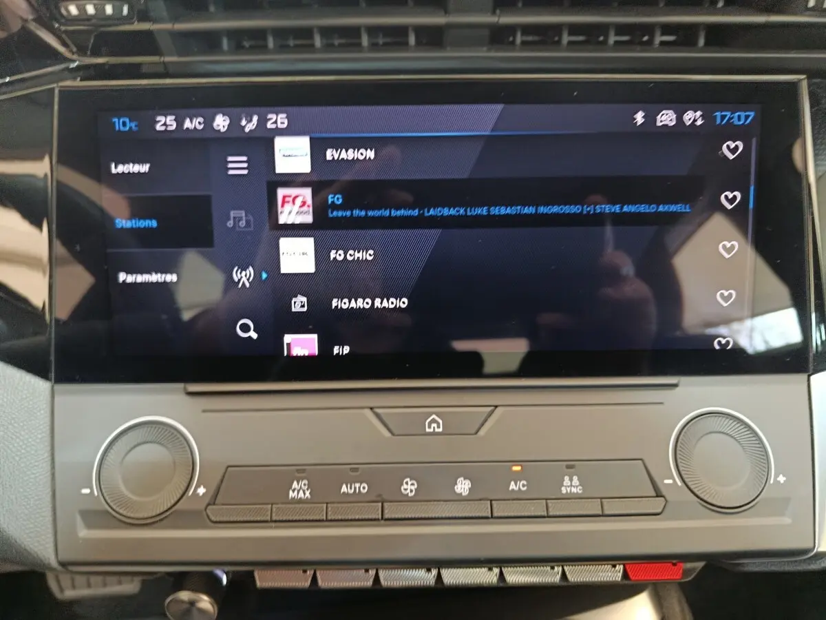 Écran tactile central affichant les stations radio dans l’habitacle d’une Peugeot 308 blanche, vue de face.