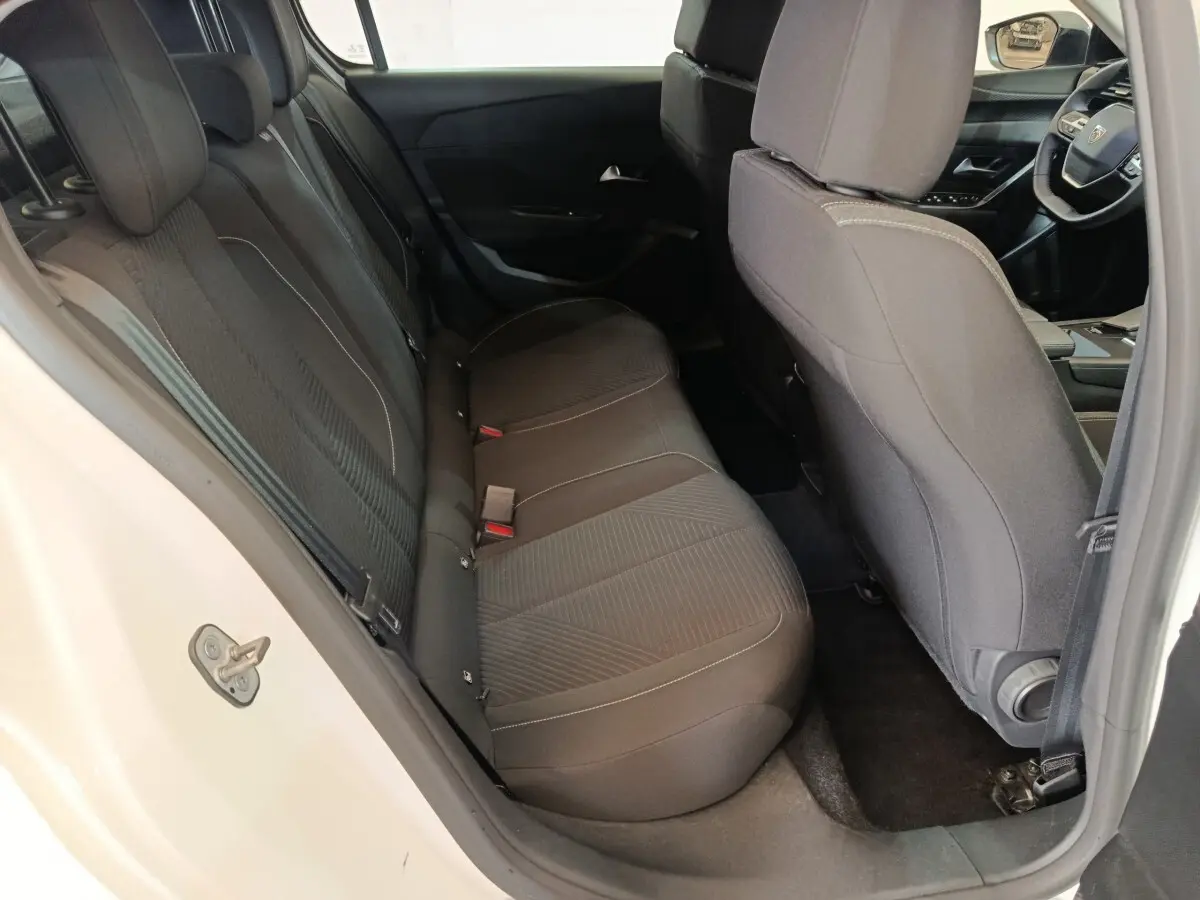Vue intérieure côté gauche sur les sièges arrière noirs d'une Peugeot 308 blanche avec tableau de bord partiellement visible.