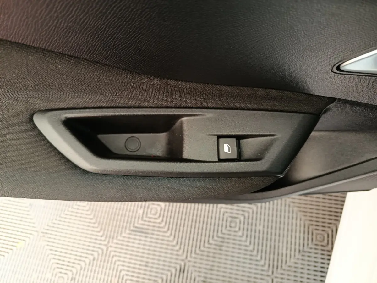 Gros plan sur la commande de lève-vitre côté droit intérieur de la Peugeot 308 blanche, version 2022.