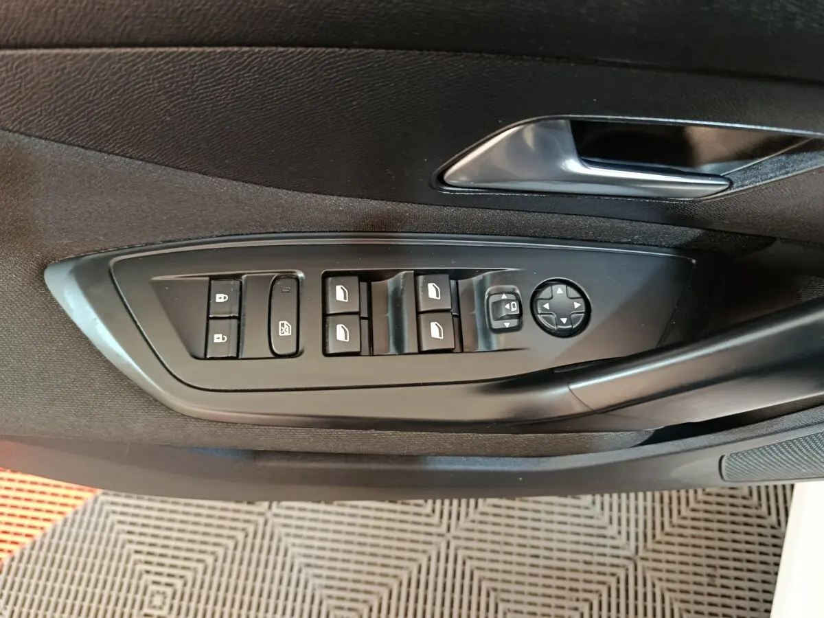 Vue rapprochée des commandes de lève-vitres et rétroviseurs côté conducteur d'une Peugeot 308 blanche de 2022.