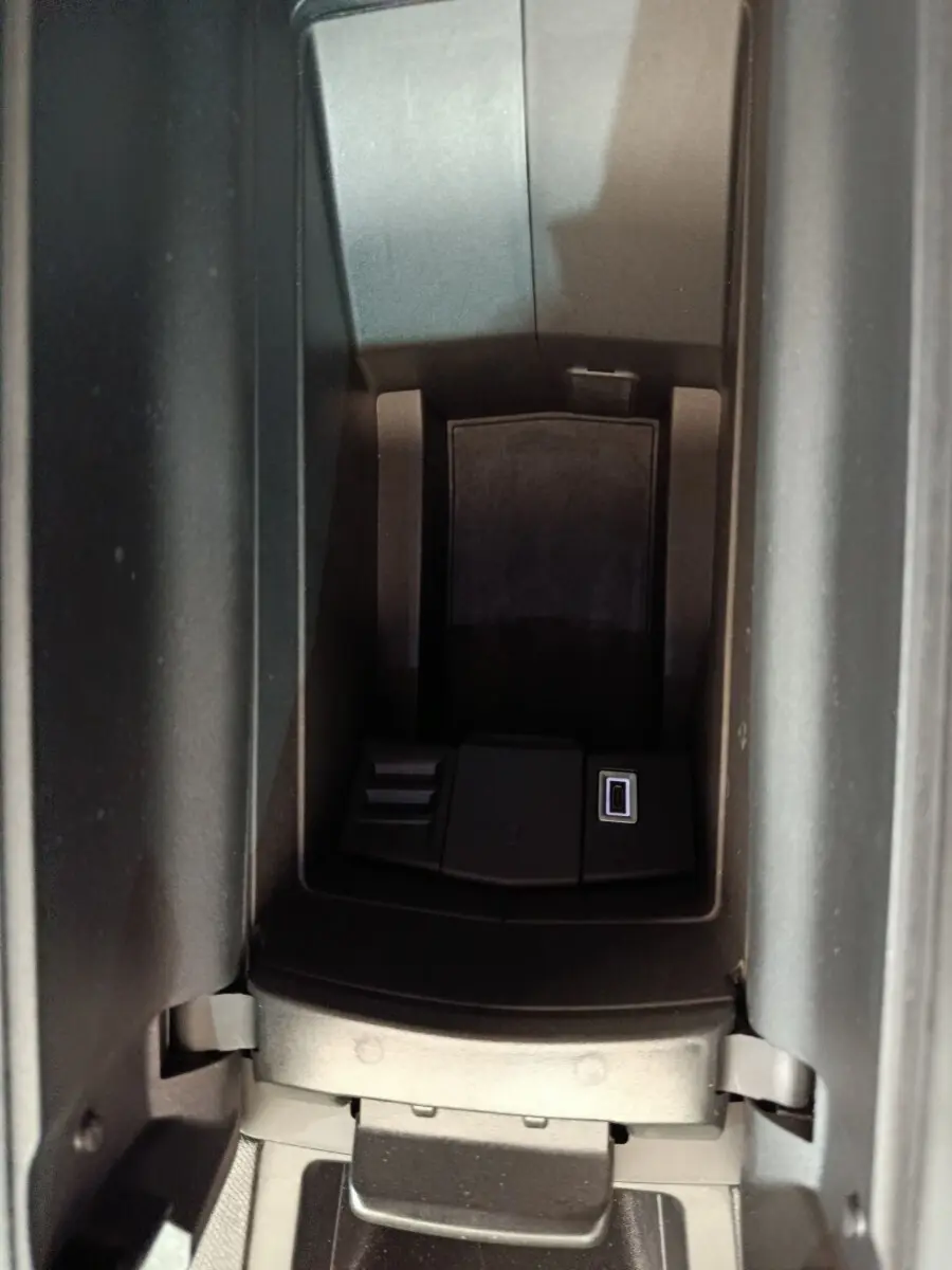 Vue rapprochée de la console centrale noire de la Peugeot 308 blanche, avec port USB visible dans l'accoudoir.