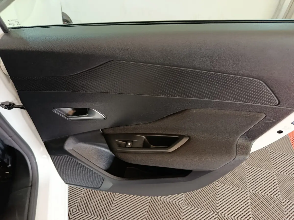 Vue intérieure côté gauche de la porte avant blanche de la Peugeot 308 avec panneau noir texturé et commande de fenêtre.