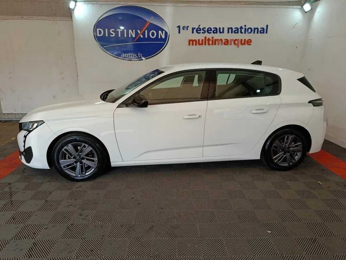 Peugeot 308 blanc vue de profil côté gauche, avec jantes alliage et feux arrière noirs distinctifs.