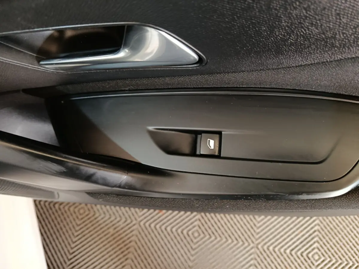 Gros plan sur la commande de lève-vitre côté conducteur de la Peugeot 308 blanche, intérieur noir.