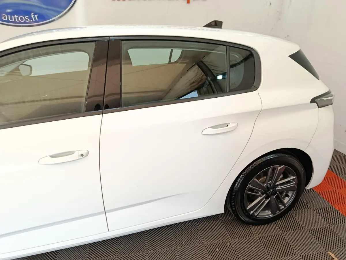 Vue latérale droite sur une Peugeot 308 blanche de 2022, mettant en valeur les vitres teintées et les jantes alliage.